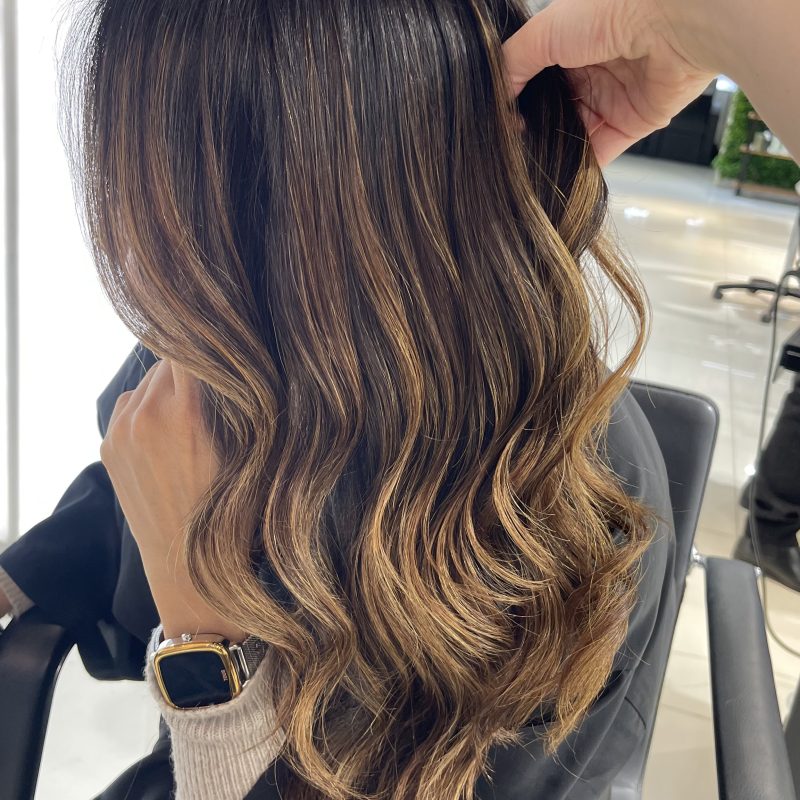Morena iluminada con reflejos dorados — Identity Peluqueros Valencia